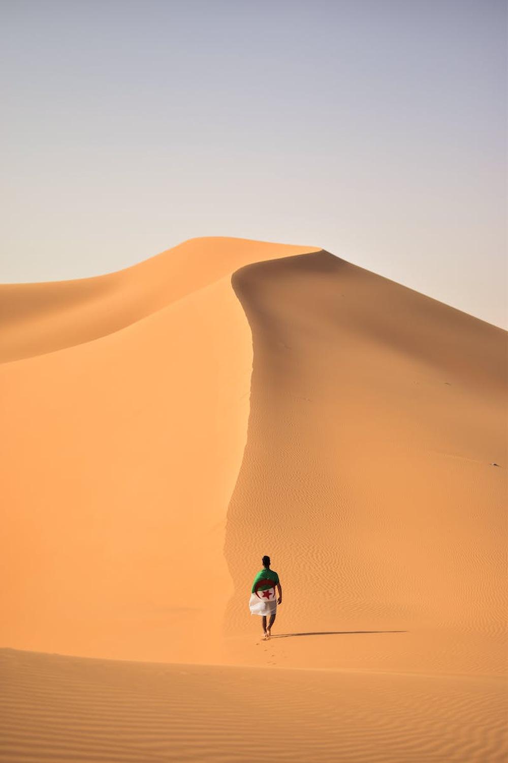 a_person_walking_in_the_middle_of_the_hot_desert