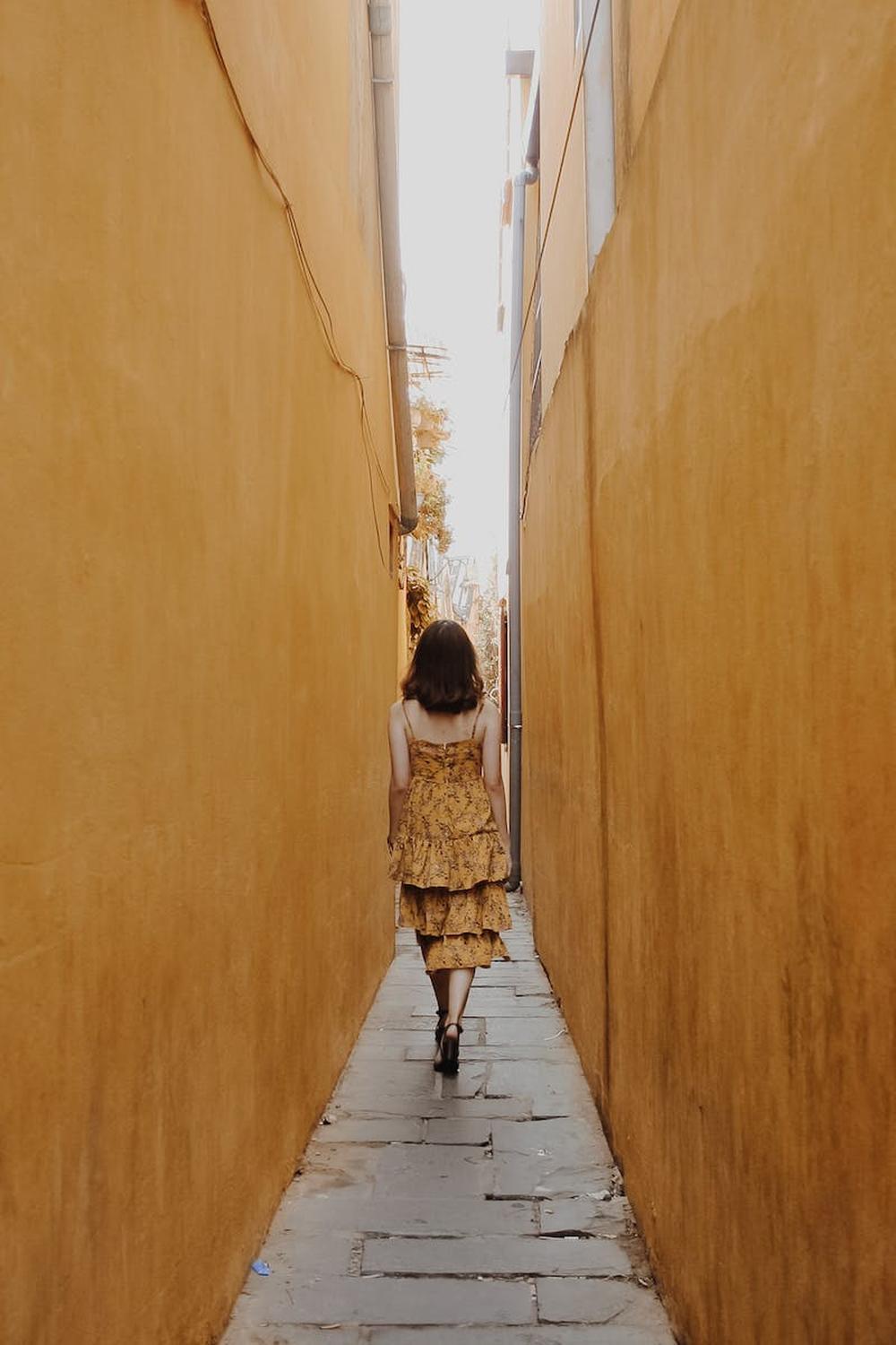back_view_of_a_woman_walking_in_a_narrow_alley
