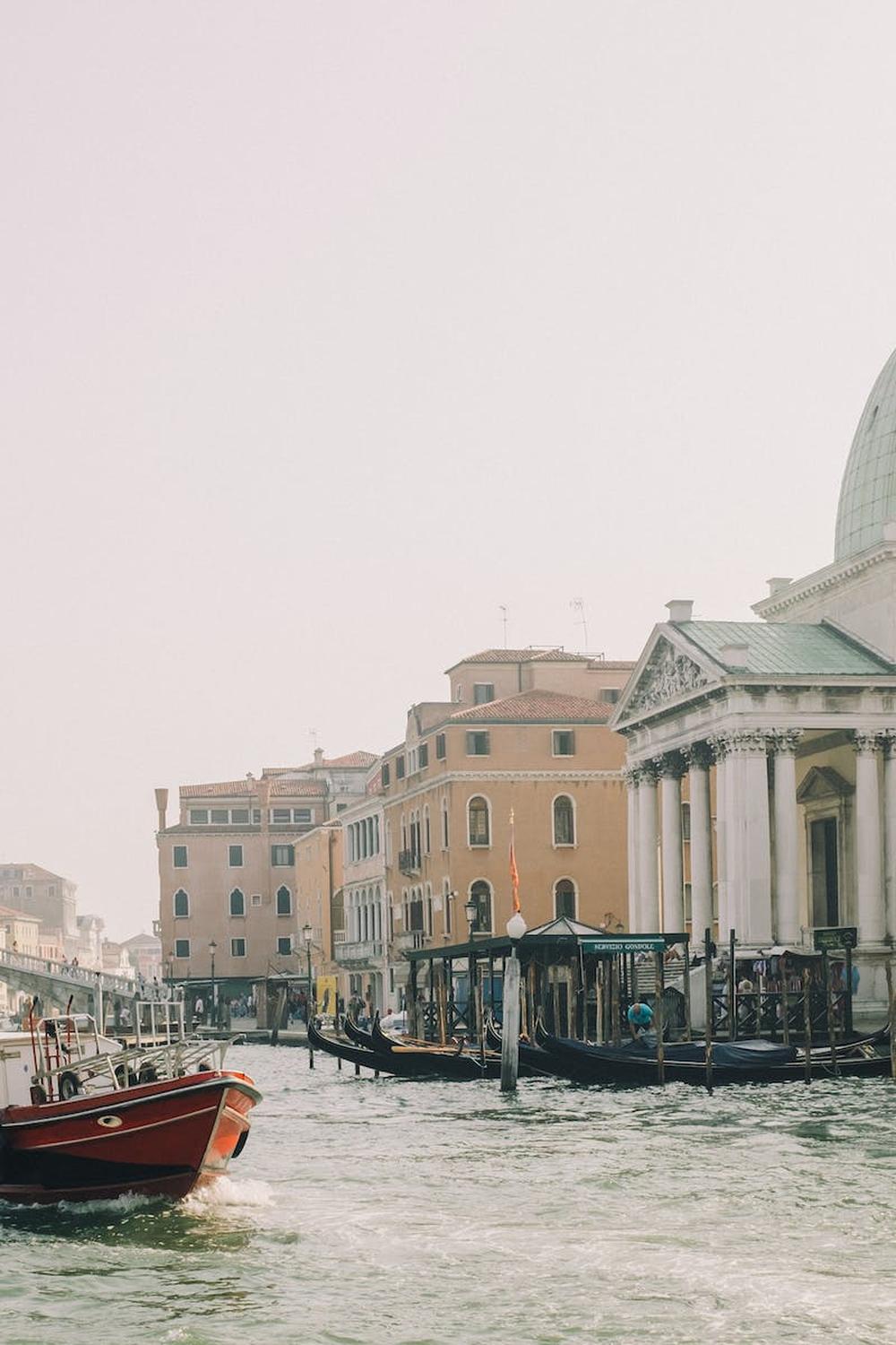 red_boat_on_body_of_water_near_white_concrete_buil