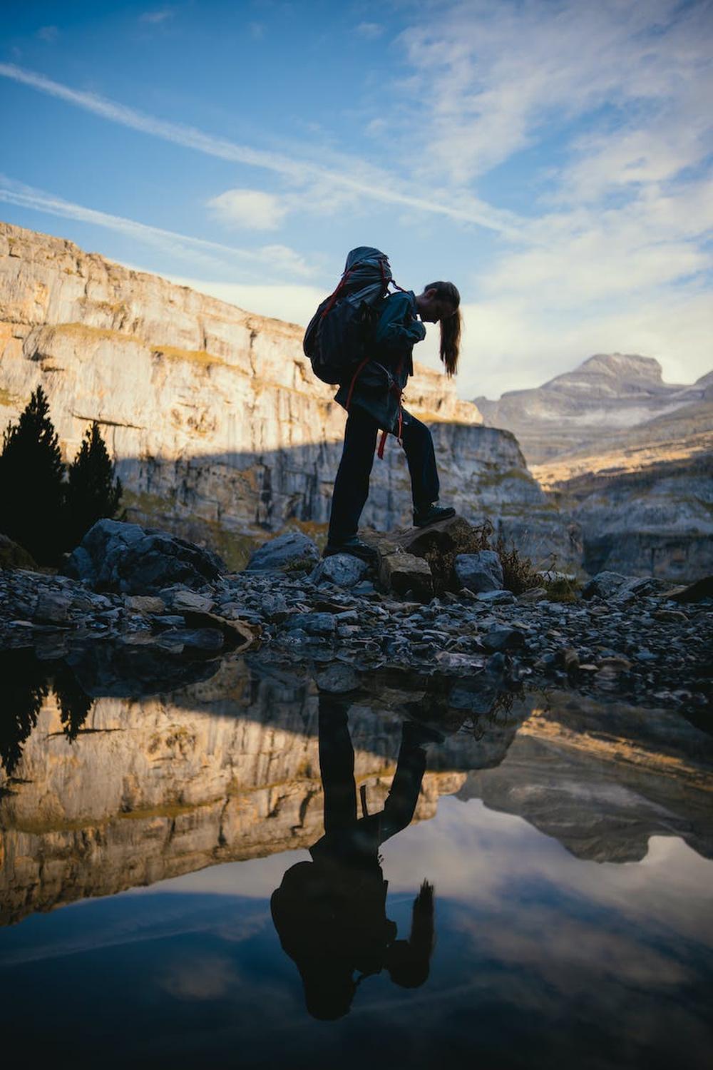 woman_in_denim_jacket_walking_on_gray_rocks_near_r