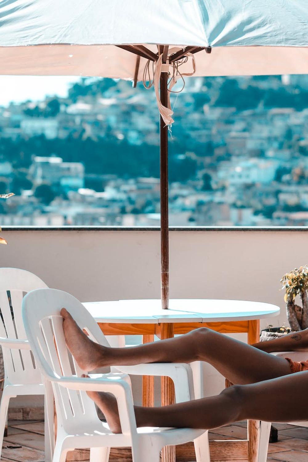 woman_sitting_on_armchair_under_white_patio_umbrel