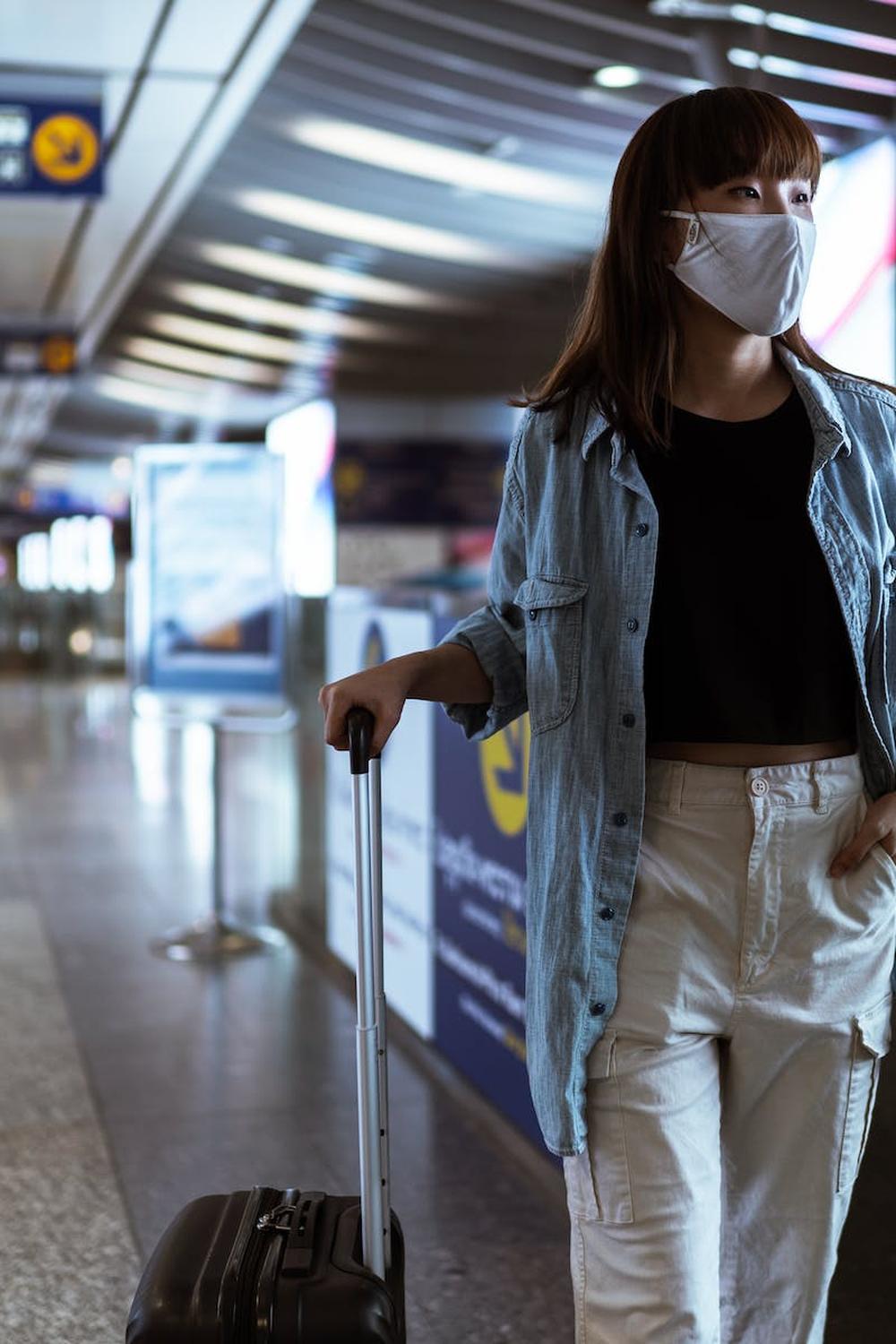 woman_with_a_face_mask_holding_her_luggage